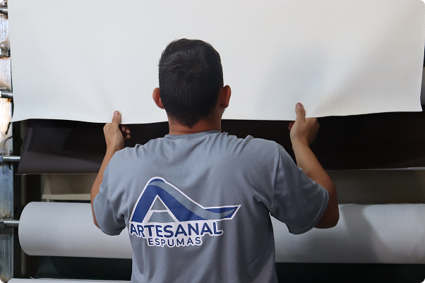 Colabodor da Artesanal Arte Espumas esticando tecido para cortar.